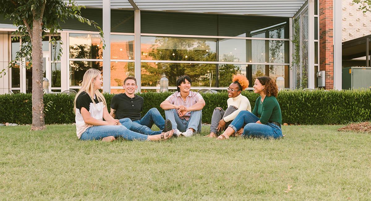 students sitting on the lawn talking